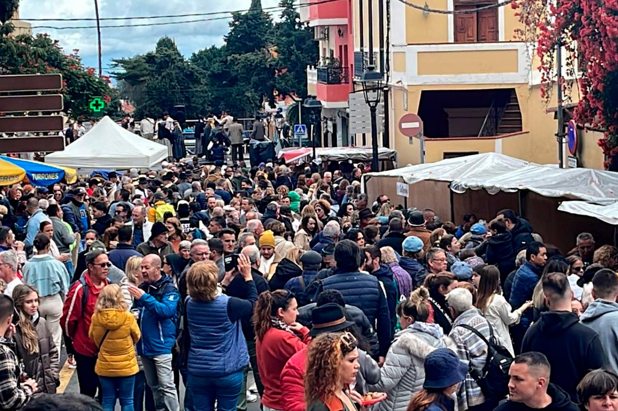 Calle del pueblo abarrotada de gente y con carpas blancas durante la Fiesta del Almendro en Flor.