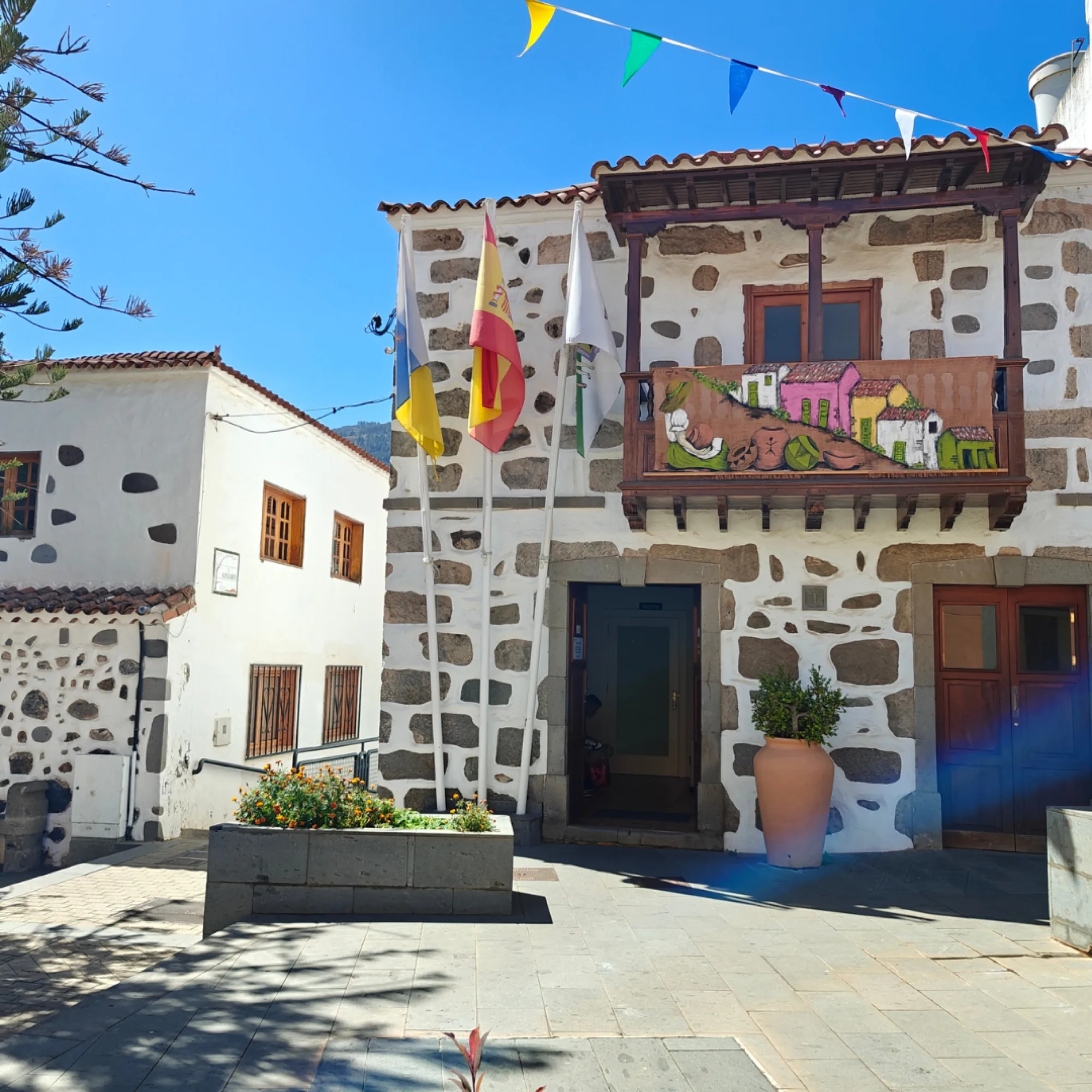 Fachada del Ayuntamiento de Valsequillo engalanada con banderas y banderines de fiesta.